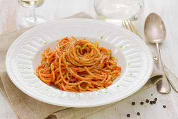 spaghetti with sauce on white plate on white wooden background