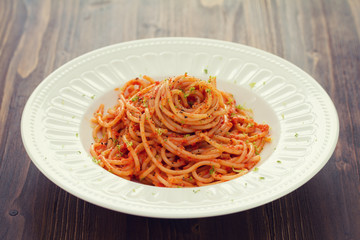 spaghetti with sauce on white plate on brown wooden background