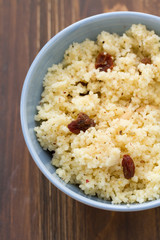 couscous with dry fruits on blue bowl on wooden background