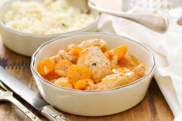 meat with carrot in bowl with fork and knife.