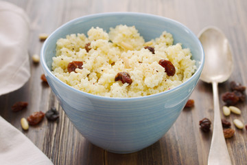 couscous with dry fruits on blue bowl on wooden background