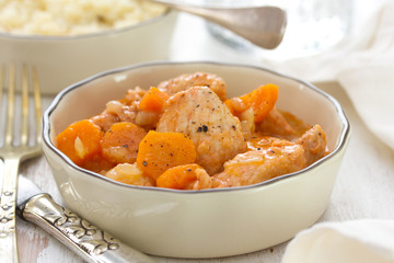 meat with carrot in bowl with fork and knife.