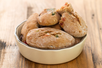 cookies with dry fruits in dish on brown background.