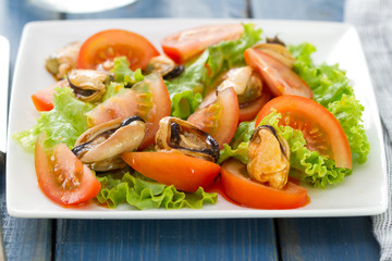 salad with tomato and mussels on white dish