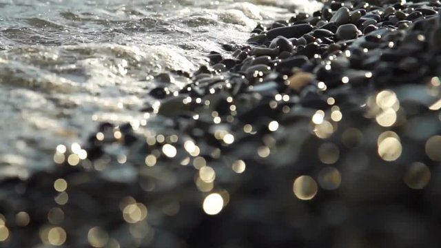 Close-up movie pebble beach with waves and drops.