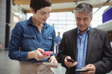 Business people holding boarding pass and using mobile phone