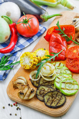 Grilled vegetables meal and ingredients on a table. Tomato, corn, eggplant, mushroom, bell pepper, marrow and onion prepared on a barbecue. Healthy food.