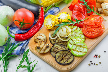 Grilled tomato, corn, eggplant, mushroom, bell pepper, marrow and onion on a table. Healthy prepared food with ingredients.