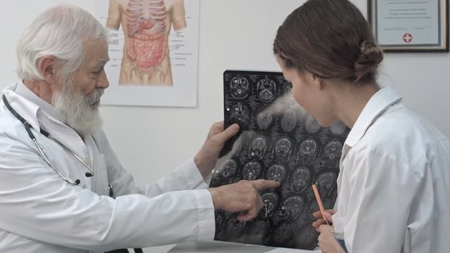 Intellectual healthcare professionals with white labcoat, looking at full body x-ray radiographic image, ct scan, mri, isolated hospital clinic background.