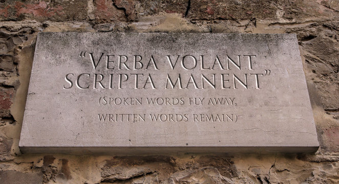 Verba volant scripta manent. Latin phrase meaning Spoken words fly away, written words remain. Engraved text.