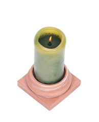 Burning green candle in clay holder separated on white background
