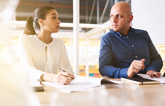 cauasian businessman paying close attention to his female business partner as she continues to explain the particulars of her new aquisition proposal of their rival company.