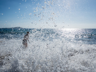 Waves crashing on the beach with a beautiful woman in background