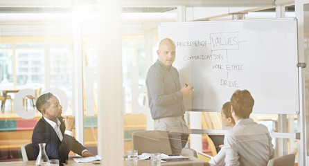 Outside office view of young caucasian man wearing a blue shirt while giveing a presentation about...
