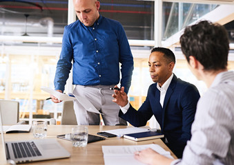 Landscape image of three diverse business partners meeting with each other to realign themselves with one and other again.