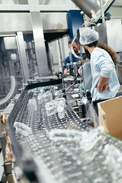 Two serious manual workers doing their job on factory production line for water purification and bottling.