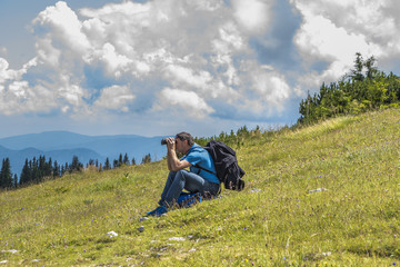 Fototapeta na wymiar Male Hiker sitting, looking through a binocular on the Rax mountain Austria