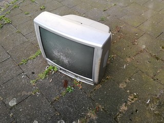 Ausrangierter alter Röhrenfernseher für den Sperrmüll auf grauem Pflasterstein des Bürgersteig...
