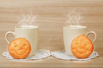 Two cups with hot drinks and cookies