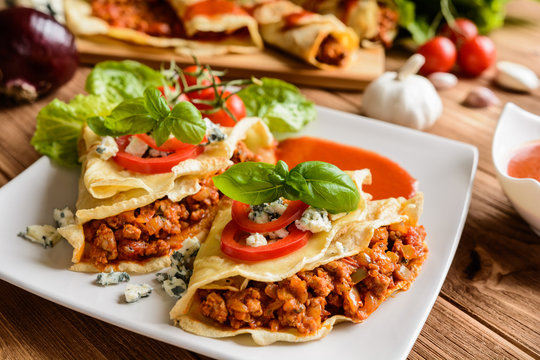 Pancakes stuffed with Bolognese filling - minced beef, pepper, onion, garlic and basil with tomato sauce