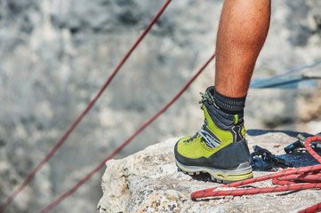 Human legs on cliff with rope.