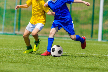 young boys playing football soccer game. Running players in blue and yellow uniforms