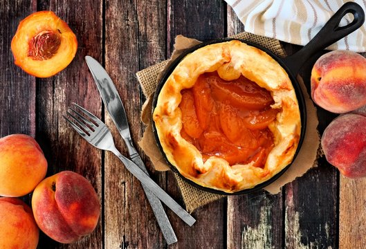 Fresh Peach Tart In Cast Iron Baking Skillet, Scene From Above On Rustic Wood