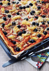 Homemade pizza with pepperoni, olives, oregano, pineapple, tomato sauce and cheese