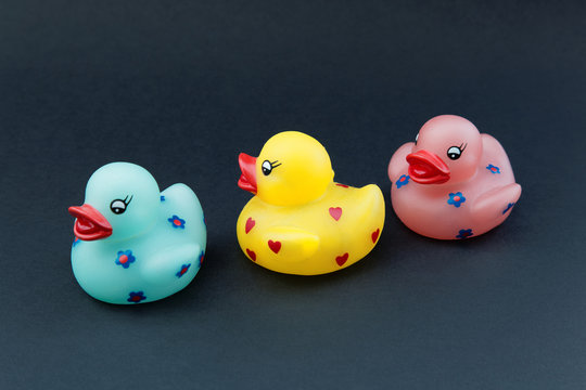 Several different colors of rubber ducks on black background