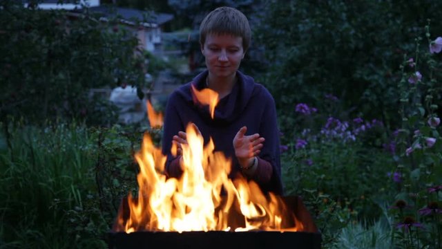 Woman warming hands near the fire in the  brazier