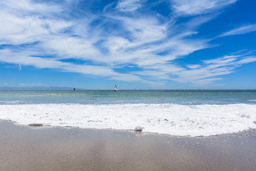 Fototapeta na wymiar Beach with White Wave and Blue Sky