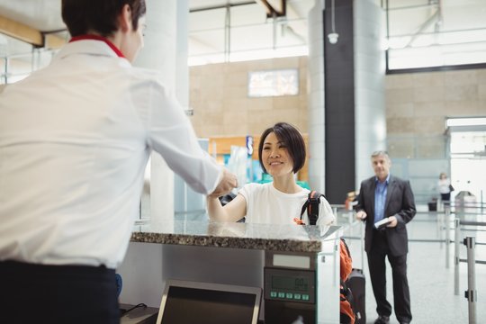 Airline check-in attendant handing passport to passenger