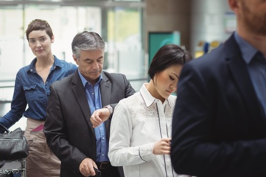 Passengers waiting in queue at a check-in counter with luggage