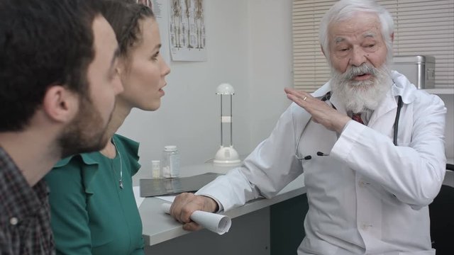 Confident doctor in front of a couple telling them how to be.
