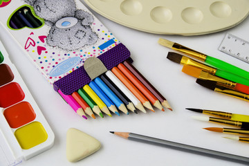 Naklejka premium A set of colored pencils and a set of colored paints for children's creativity.