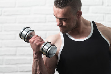 Man Exercising Biceps On White Bricks Background