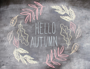 Chalk pattern of hello autumn inside autumn leaves on slate