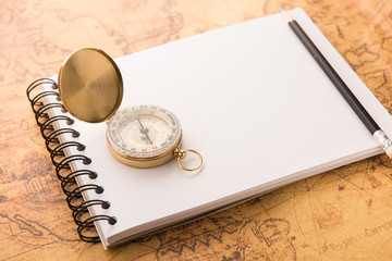Compass with note book and pencil on old map vintage style
