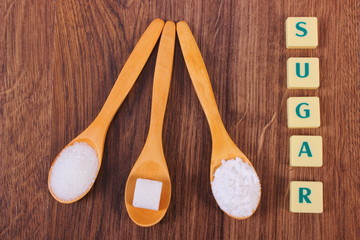Sugar cube, granulated and powdered sugar on wooden spoons
