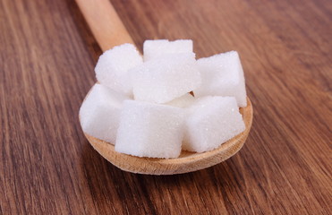 Cubes of sugar on wooden background, ingredient for cooking