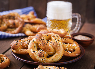 Oktoberfest salted soft pretzels in a bowl and beer from Germany on wooden background.