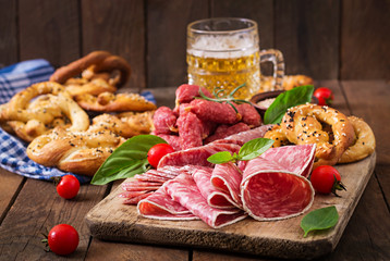 Glass of beer, pretzels and various sausages on wooden background. Oktoberfest.