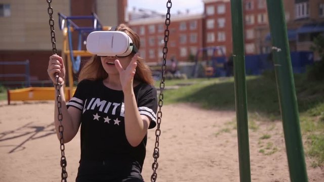 Handsome young woman playing VR attraction swinging outdoors. Virtual reality 3D modern technology. HD.