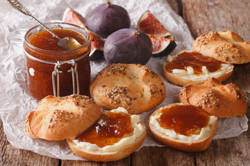 Glass jar with some fig jam and sweet buns close-up. Horizontal
