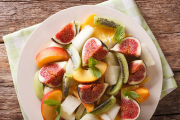 Sliced fresh fruit: figs, peaches, melons, kiwi and orange closeup. horizontal top view
