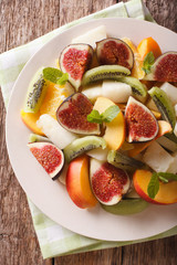 Sliced fresh fruit: figs, peaches, melons, kiwi and orange close-up. vertical top view
