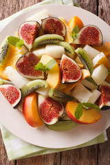Salad of ripe fruit: figs, peaches, melons, kiwi and orange close-up. vertical top view
