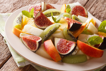 Fresh fruit salad of figs, peaches, melons, kiwi and orange close-up. horizontal

