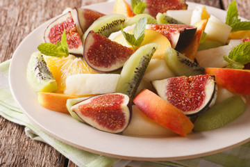 Delicious sliced fruit fig, peach, melon, kiwi and orange close-up. horizontal
