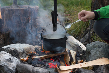 girl prepares in a cauldron on the fire, near the ax in a log